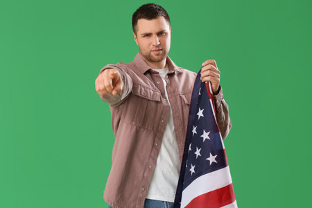Young man with USA flag pointing at viewer on green background. Accusation conceptの写真素材