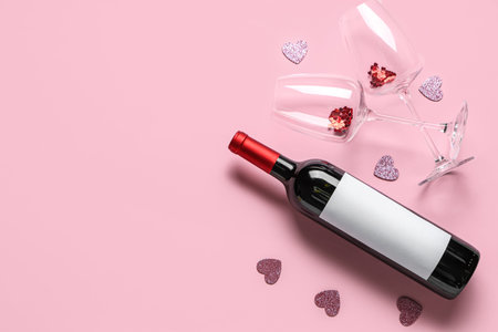 Bottle of wine with glasses and decor on pink background. Valentine's Day celebrationの写真素材