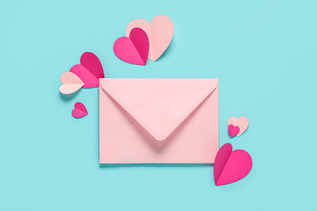 Composition with pink envelope and paper hearts on color background. Valentine's Day celebrationの写真素材