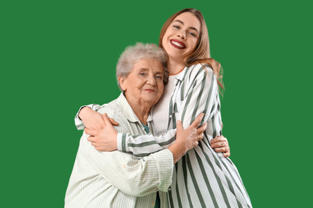 Young woman hugging her grandmother on green backgroundの写真素材