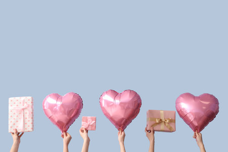 Female hands with gift boxes and heart shaped air balloons on blue background. Valentine's Day celebrationの写真素材