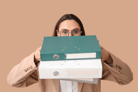 Young businesswoman with document folders on beige backgroundの写真素材
