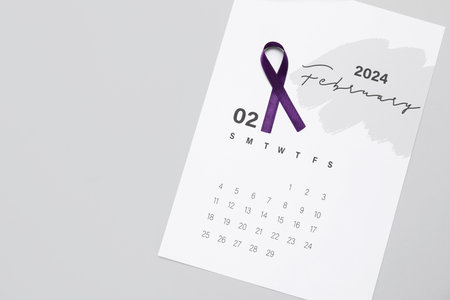 Purple ribbon and paper calendar on gray background. Cancer awareness conceptの写真素材