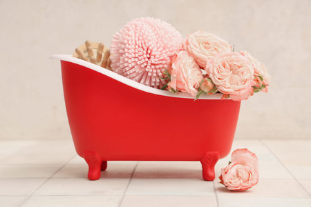 Mini bathtub with bath supplies and roses on white tile near wall. Valentine's Day celebration