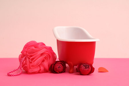 Mini bathtub with sponge and roses on color background. Valentine's Day celebration