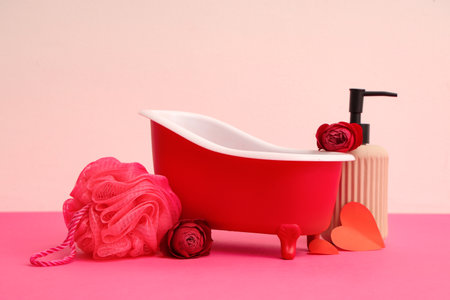 Mini bathtub with bath supplies and roses on color background. Valentine's Day celebrationの写真素材