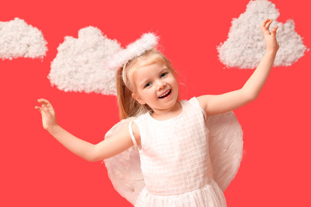 Cute little girl dressed as cupid with clouds on red background. Valentine's Day celebrationの写真素材