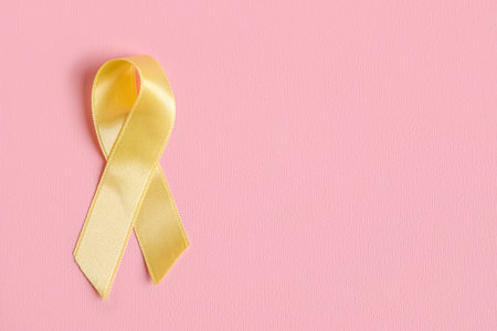 Golden ribbon on pink background. Childhood cancer awareness conceptの写真素材