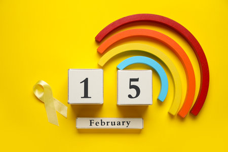 Date of Childhood cancer awareness day with golden ribbon and toys on yellow backgroundの写真素材