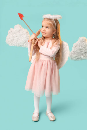 Cute little girl dressed as cupid with arrow, bow and clouds on blue background. Valentine's Day...