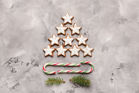 Christmas tree made of stars shaped cookies with candy canes on gray grunge background