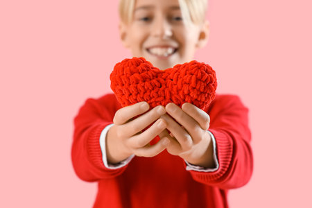 Cute little boy with red heart for Valentine's day on pink backgroundの写真素材