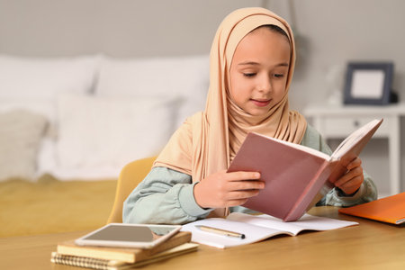 Little Muslim girl in hijab doing homework at homeの写真素材