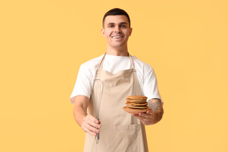 Young man with tasty homemade pancakes and whiskey on yellow backgroundの写真素材