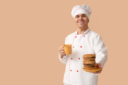 Male chef with tasty pancakes and tea on beige backgroundの写真素材