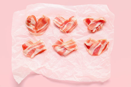 Paper with hearts made of tasty bacon on pink background