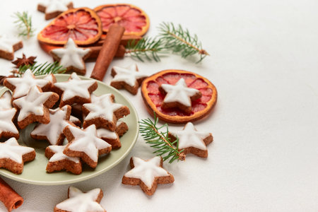 Plate with delicious stars shaped Christmas cookies, orange dried pieces and fir tree branches on light background, closeupの写真素材