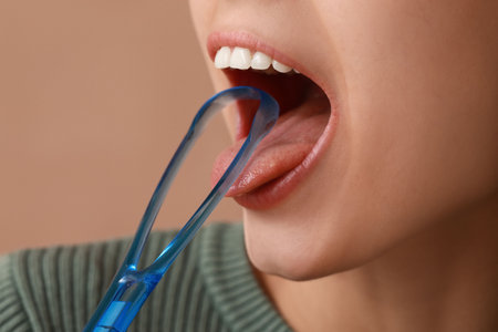 Young woman with tongue scraper on brown backgroundの写真素材