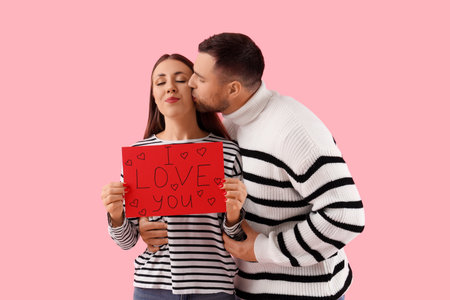 Lovely couple holding greeting card with text I LOVE YOU on pink background. Valentine's Day celebrationの写真素材