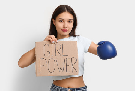 Young woman with sign GIRL POWER and boxing glove on white background. Feminism conceptの写真素材