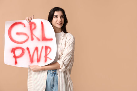 Young woman with sign GRL PWR on beige background. Feminism conceptの写真素材
