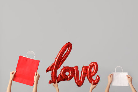 Women with the word LOVE and shopping bags on light background. Valentine's Day celebrationの写真素材