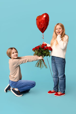 Little boy greeting girl with roses on blue background. Valentine's Day celebrationの写真素材