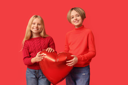 Little children with heart-shaped balloon on red background. Valentine's Day celebrationの写真素材
