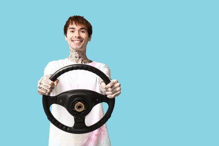 Handsome young man with steering wheel on blue backgroundの写真素材