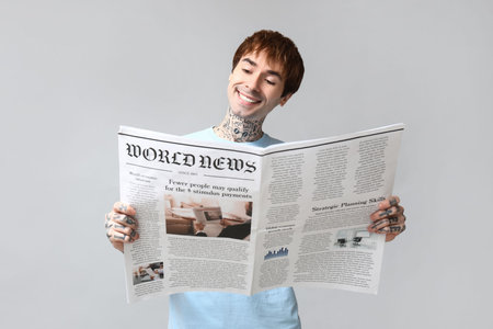 Handsome young man with newspaper on gray backgroundの写真素材