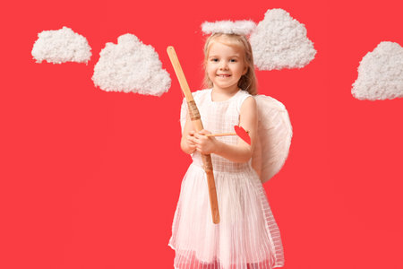 Cute little girl dressed as cupid with arrow, bow and clouds on red background. Valentine's Day celebrationの写真素材