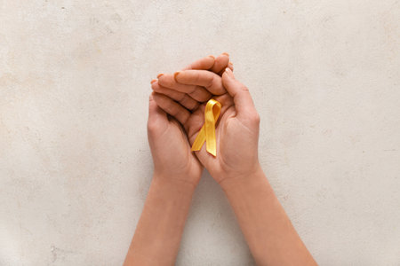 Hands with golden ribbon on white grunge background. Childhood cancer awareness conceptの写真素材