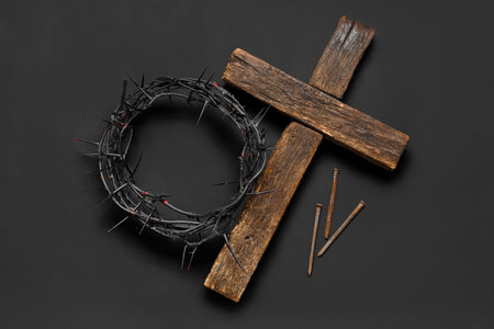 Wooden cross with crown of thorns and nails on black background. Good Friday concept