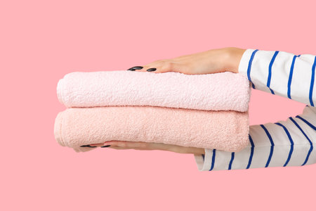 Female hands with clean towels on pink backgroundの写真素材