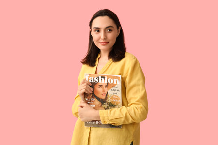 Beautiful woman with fashion magazine on pink backgroundの写真素材