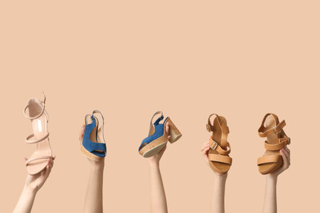 Female hands with different stylish shoes on beige background. Shoe repair conceptの写真素材