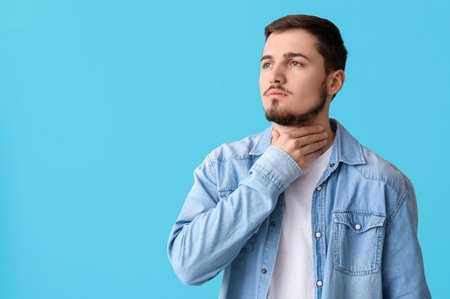 Young man with thyroid gland problem on blue background