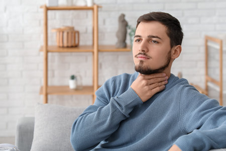 Young man with thyroid gland problem at home
