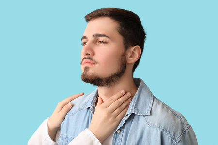 Endocrinologist examining thyroid gland of young man on blue backgroundの写真素材