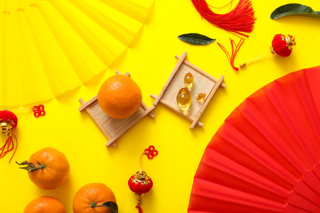 Composition with paper fans, tangerines and Chinese symbols on yellow background. New Year celebrationの写真素材
