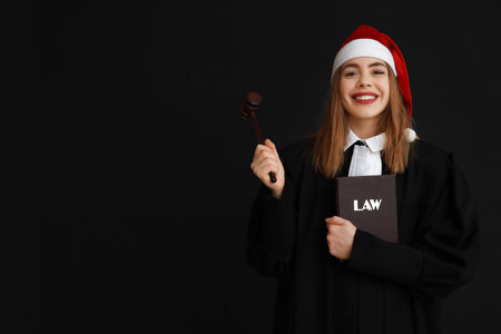 Young female judge in Santa hat on black backgroundの写真素材