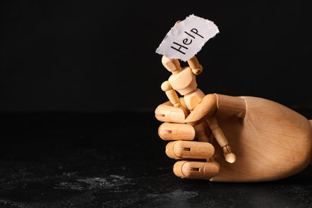 Paper piece with word HELP, wooden mannequin and hand on dark background. Domestic violence conceptの写真素材