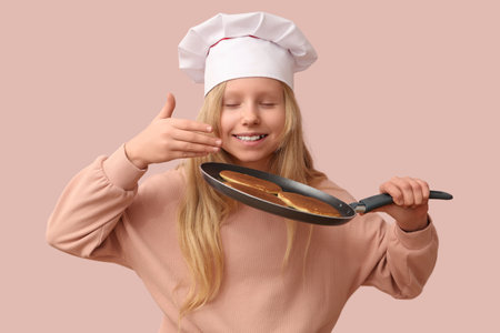 Little chef with tasty pancakes on frying pan against beige backgroundの写真素材