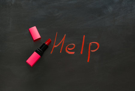 Written word HELP with lipstick on dark background. Domestic violence conceptの写真素材
