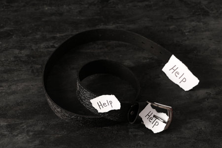 Paper pieces with word HELP and belt on dark background. Domestic violence conceptの写真素材