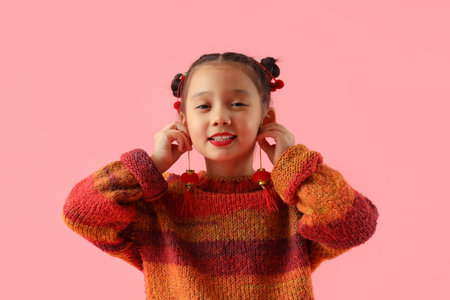Cute little Asian girl with Chinese symbols on pink background. New Year celebration