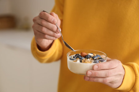 Young man with tasty yogurt in kitchen, closeup