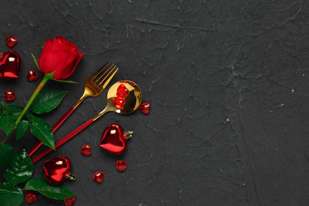 Cutlery with hearts and red rose on black background. Valentine's Day celebrationの写真素材