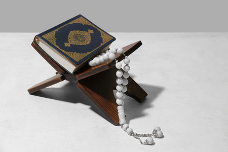 Rehal with Koran and prayer beads for Ramadan on white table