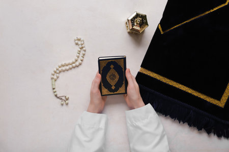 Female hands with Koran, prayer beads and Muslim lantern for Ramadan on white backgroundの写真素材